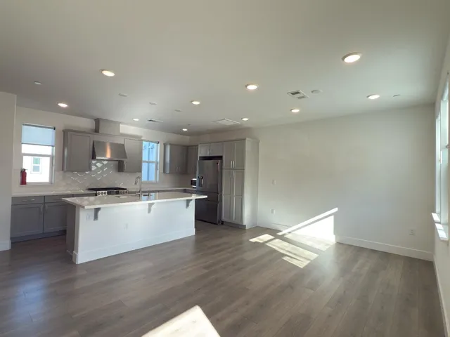 a large kitchen with a wooden floor and stainless steel appliances