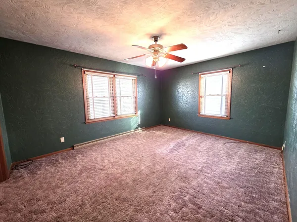 a bedroom with a chandelier fan and windows