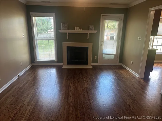 an empty room with wooden floor fireplace and windows