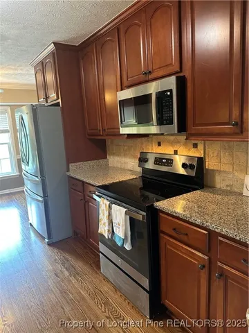 a kitchen with stainless steel appliances granite countertop a stove microwave and refrigerator