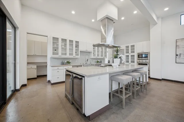 a kitchen with stainless steel appliances a stove a sink a refrigerator and white cabinets with wooden floor