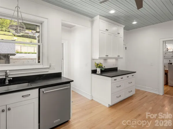 a kitchen with granite countertop white cabinets and window