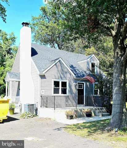 a front view of a house with garden and trees