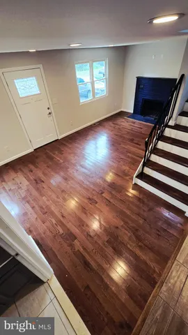 a view of an empty room with wooden floor and window