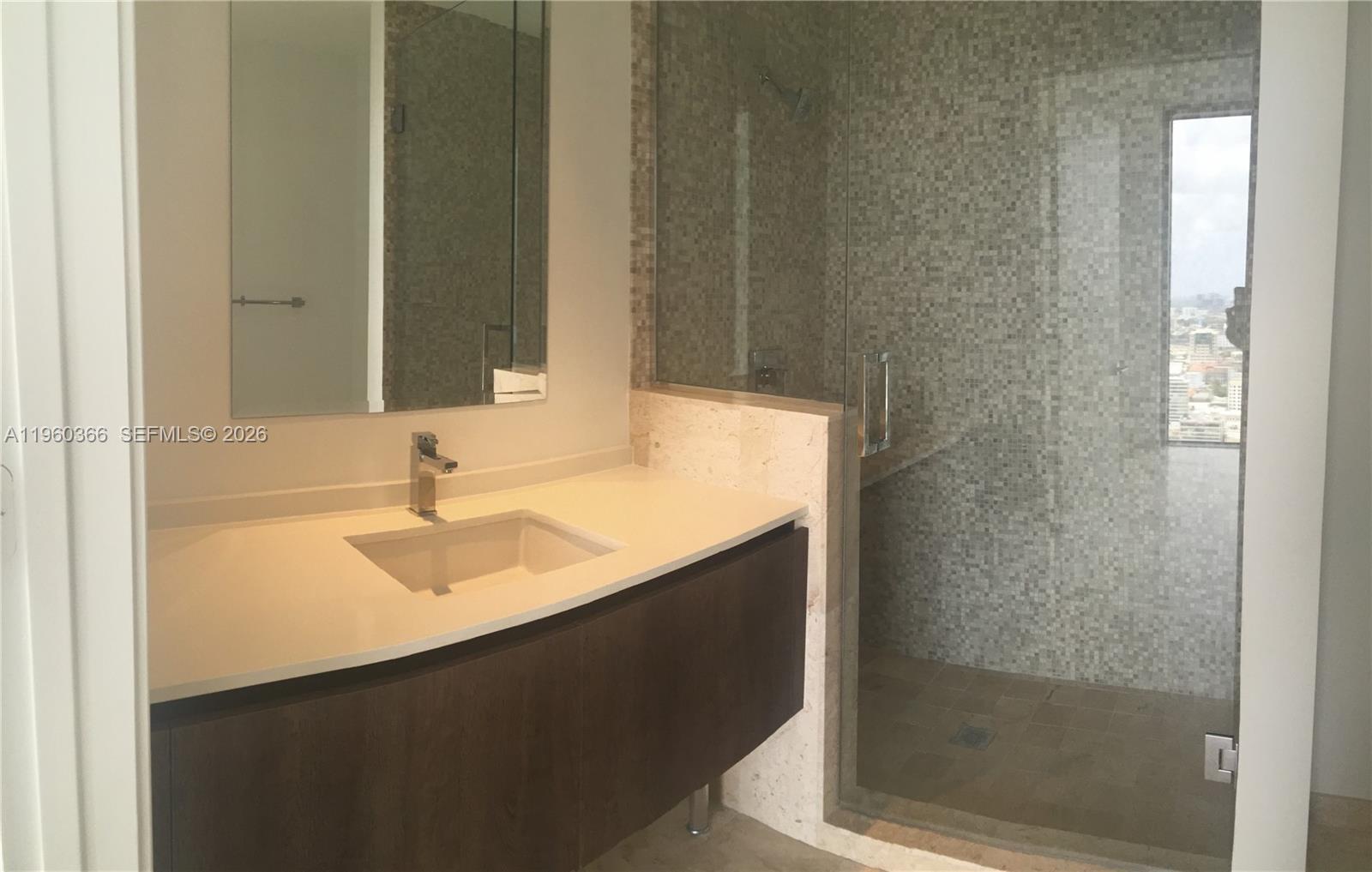 68 Southeast 6th Street, Unit 3412 Miami, FL 33131 - Photo 7 of 13 a bathroom with a sink and a mirror