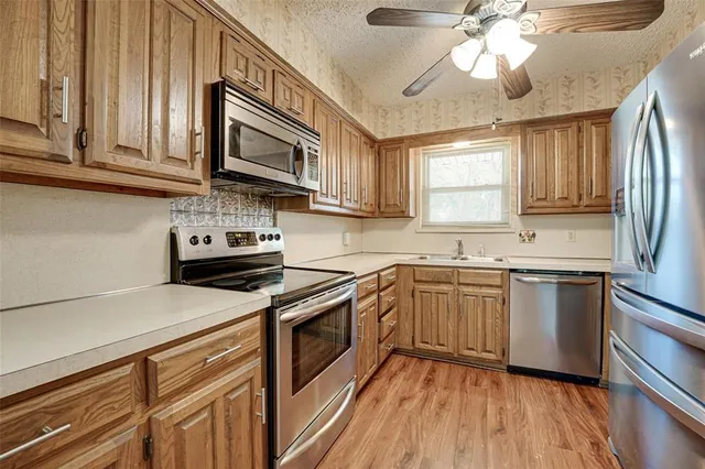 a kitchen with stainless steel appliances granite countertop a sink cabinets a stove and a refrigerator