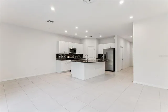 a kitchen with stainless steel appliances kitchen island sink refrigerator and cabinets