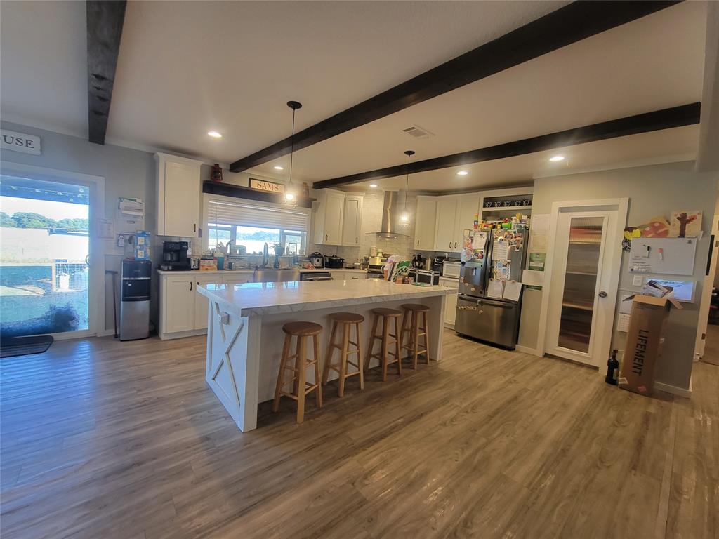150 Hawkins Chapel Road Loving, TX 76460 - Photo 13 of 40 a kitchen with stainless steel appliances kitchen island granite countertop wooden floors and wooden cabinets
