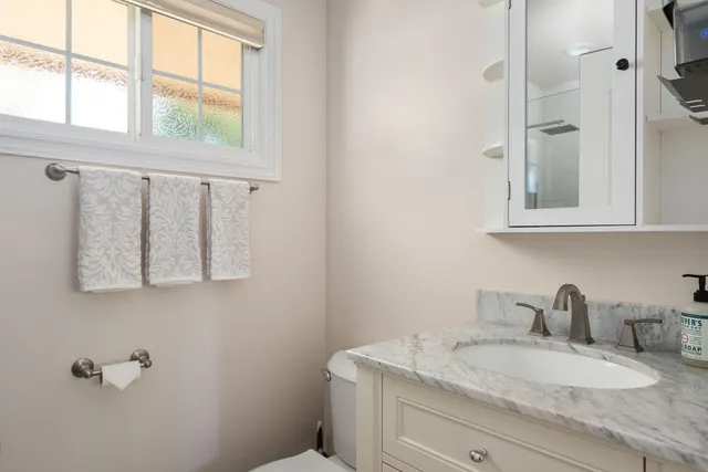 a bathroom with a granite countertop sink mirror vanity and window