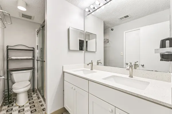 a bathroom with a sink toilet double vanity and shower