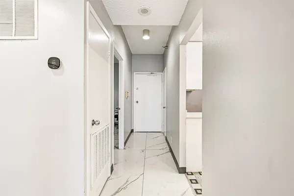 a view of a hallway with a door and a bathroom