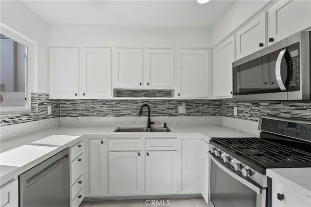 a kitchen with white cabinets and appliances