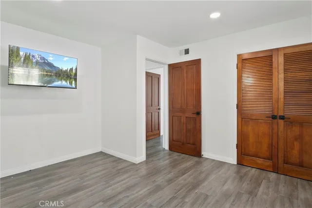 a view of an empty room with wooden floor and closet area