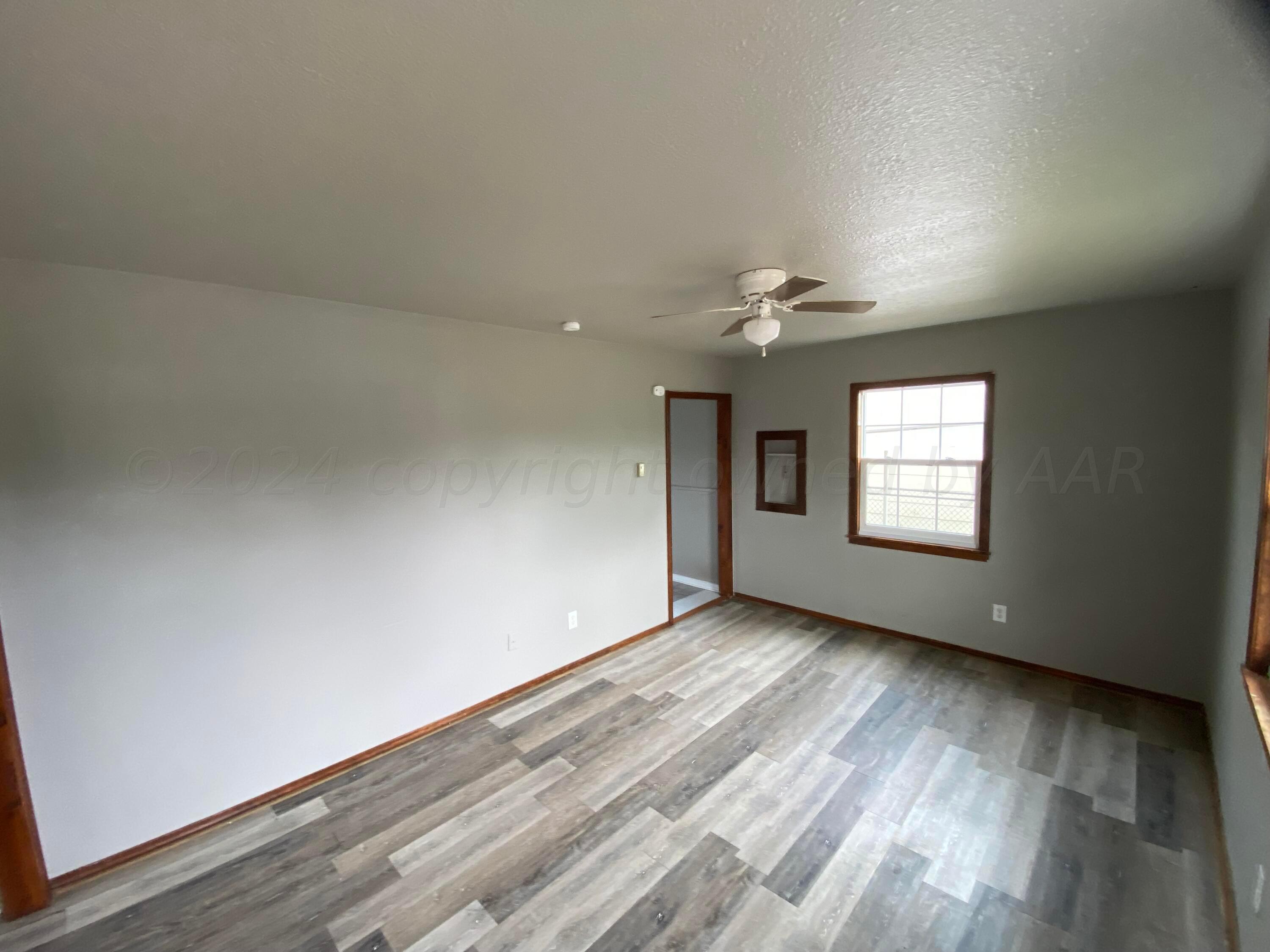 1010 Ricks Street Amarillo, TX 79104 - Photo 2 of 8 an empty room with wooden floor and windows