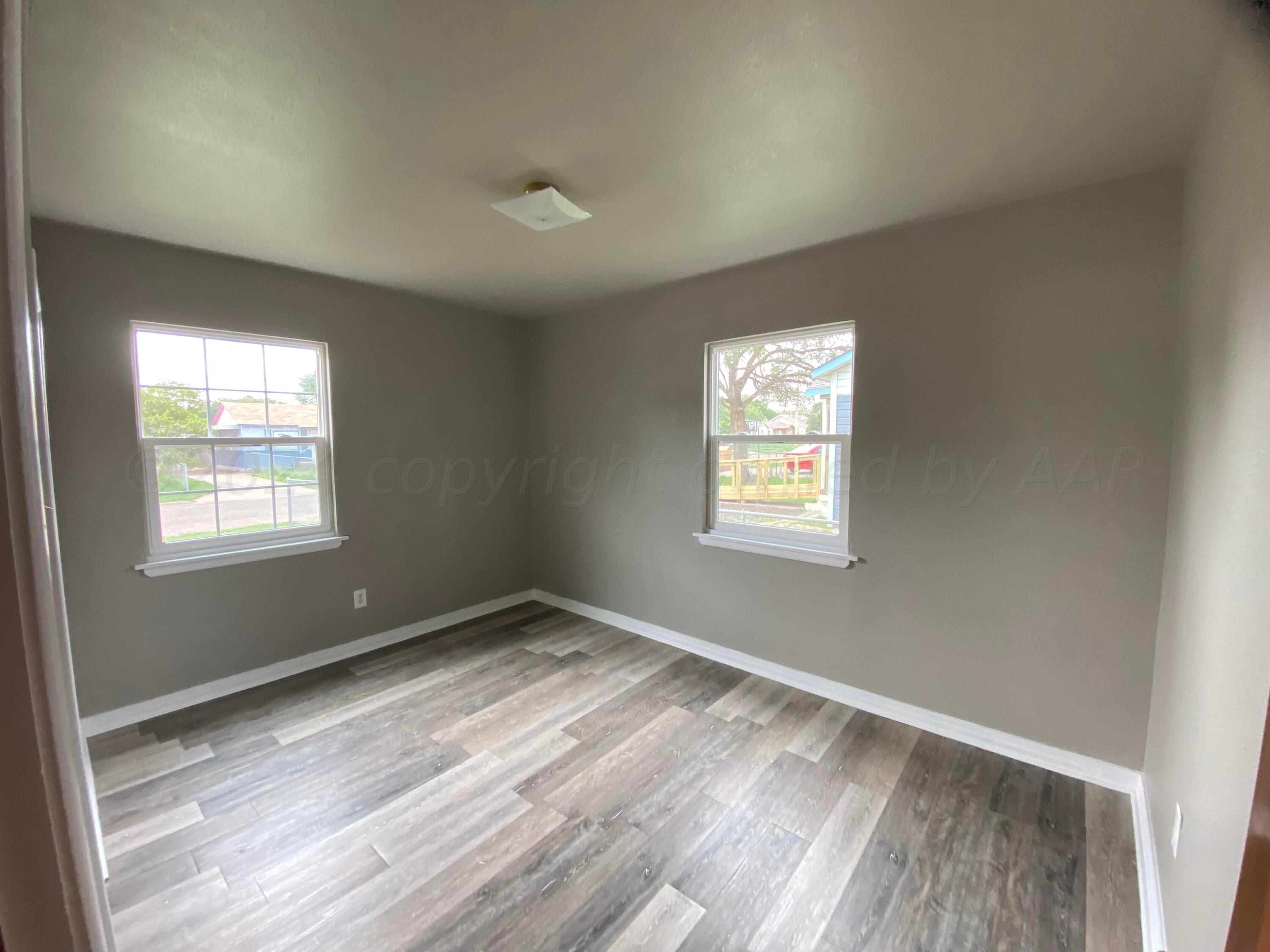 1010 Ricks Street Amarillo, TX 79104 - Photo 4 of 8 an empty room with wooden floor and windows