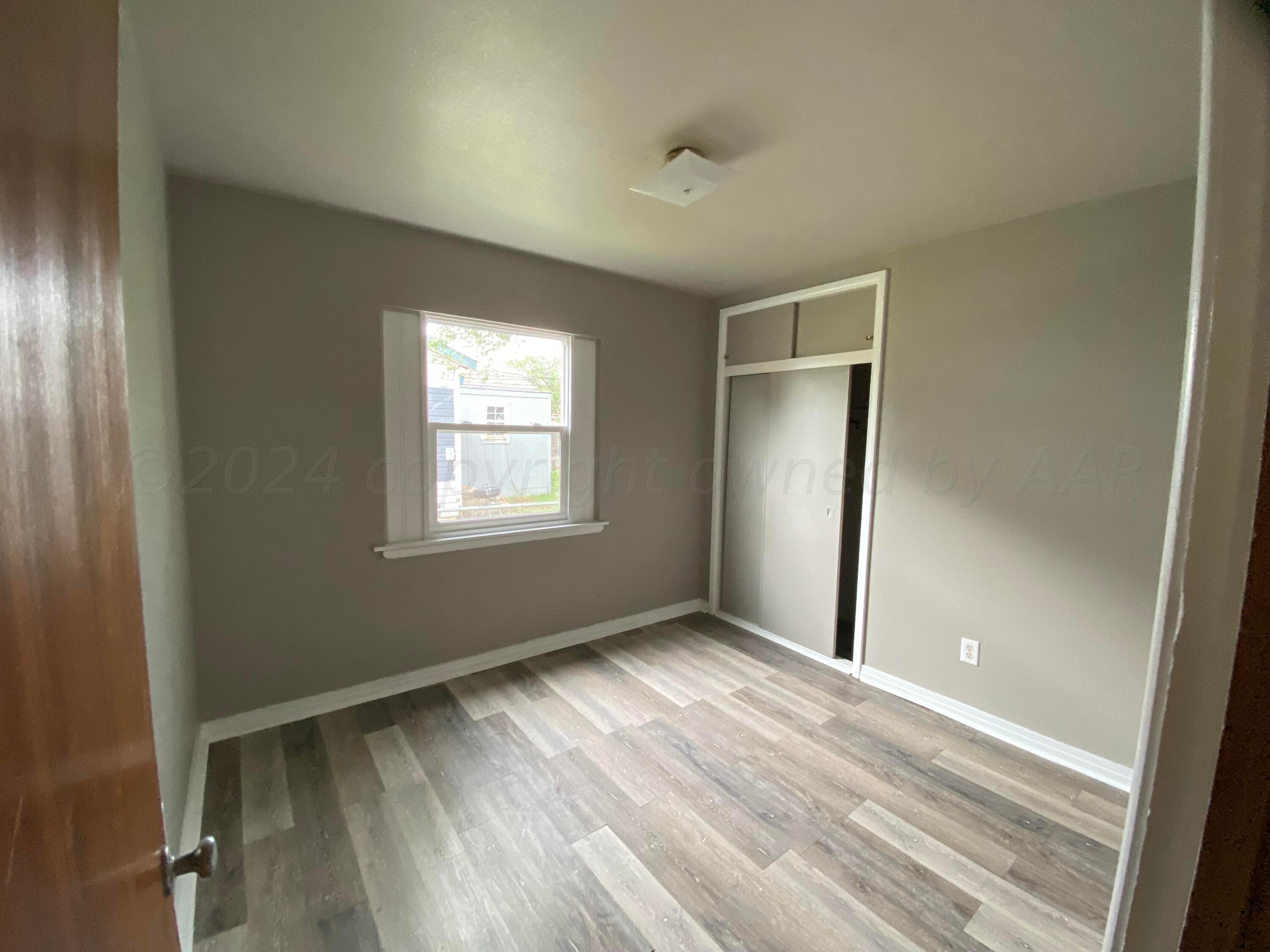 1010 Ricks Street Amarillo, TX 79104 - Photo 5 of 8 an empty room with wooden floor and windows