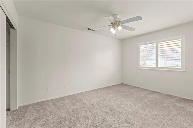 an empty room with a window and a fan