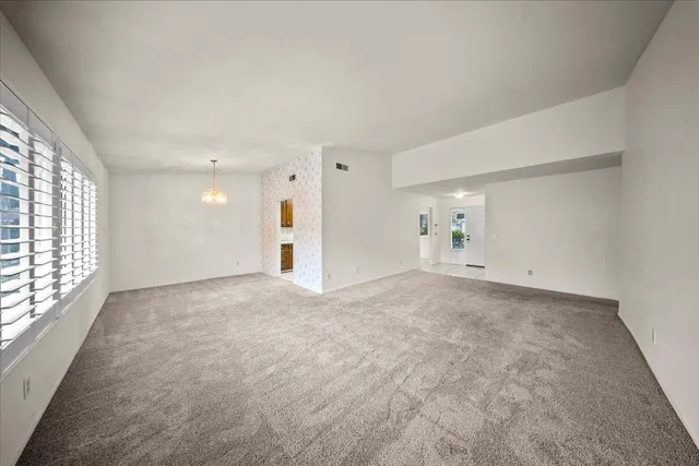 an empty room with windows and refrigerator