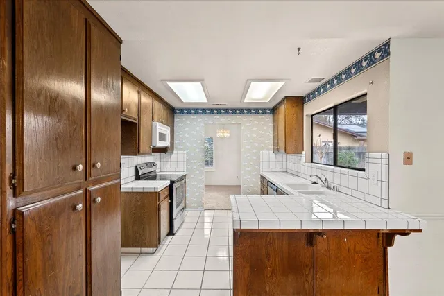 a large kitchen with stainless steel appliances kitchen island granite countertop a refrigerator and a stove top oven