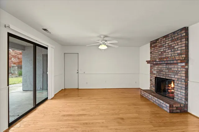 a view of empty room with wooden floor and fireplace