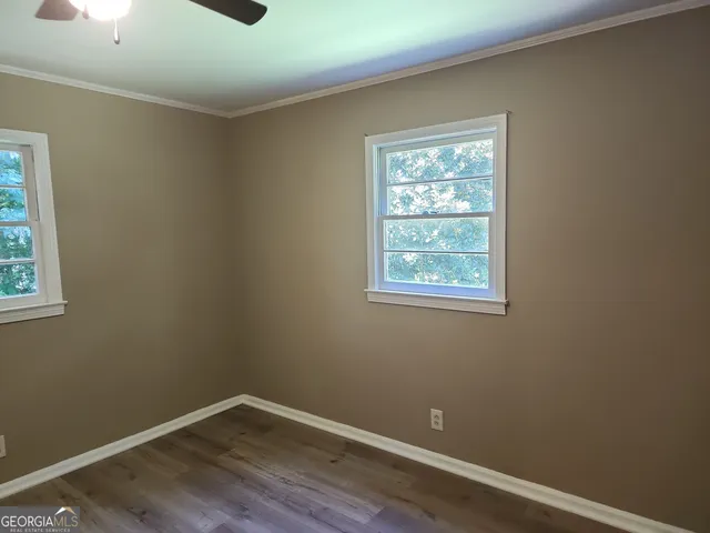 an empty room with wooden floor and a ceiling fan