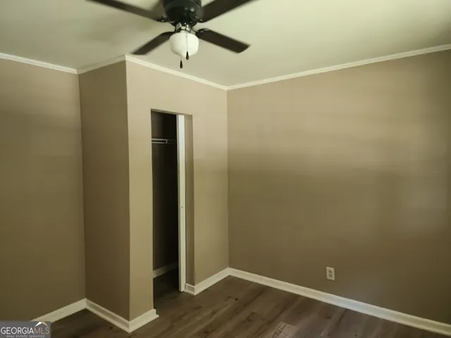 an empty room with wooden floor and fan