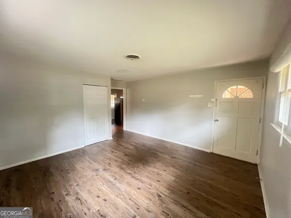 an empty room with wooden floor and windows