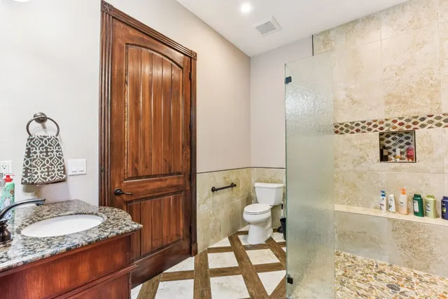 a bathroom with a granite countertop sink toilet and shower