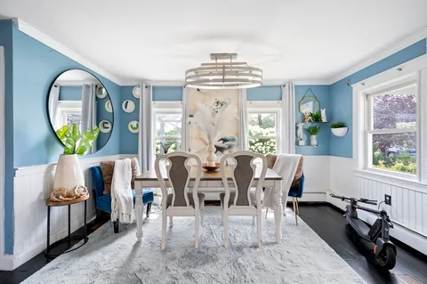 a dining room with wooden floor a chandelier a wooden table and chairs