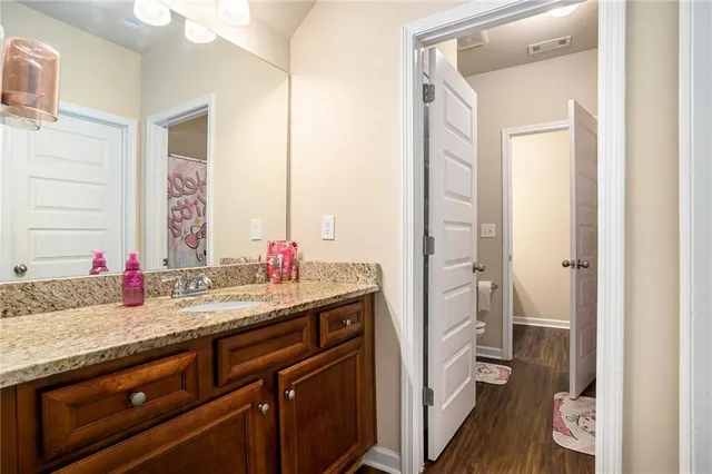 a bathroom with a granite countertop sink a toilet and a mirror