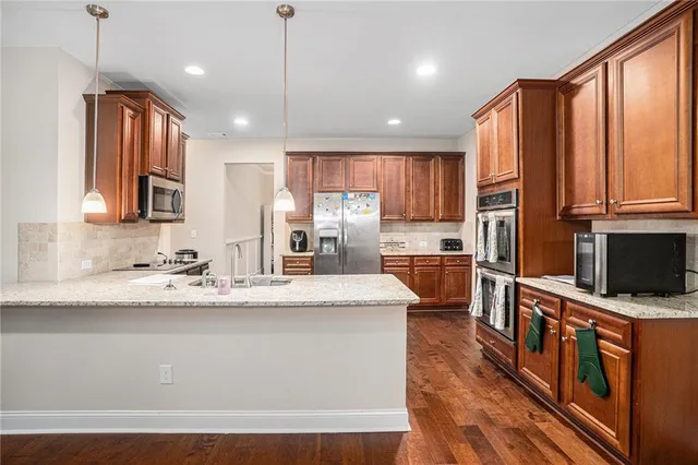 a kitchen with stainless steel appliances granite countertop a sink a stove and a refrigerator
