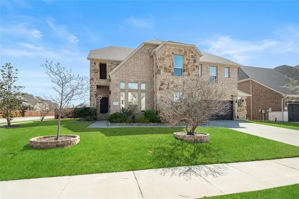 a front view of a house with garden and trees