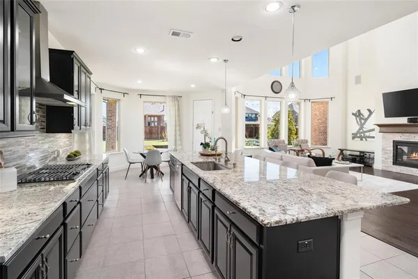 a kitchen with granite countertop kitchen island a stove a sink a dining table and chairs