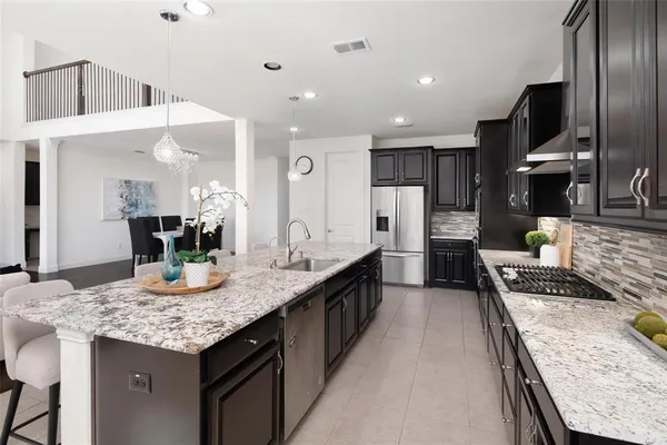 a kitchen with granite countertop kitchen island stainless steel appliances a sink stove and cabinets