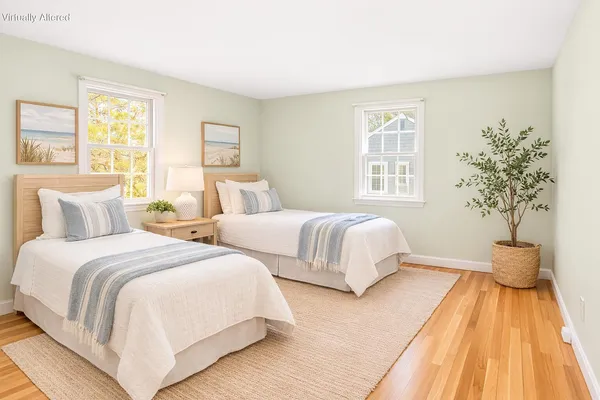 a bedroom with two beds and a potted plant