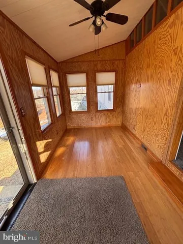 a view of empty room with wooden floor and fan