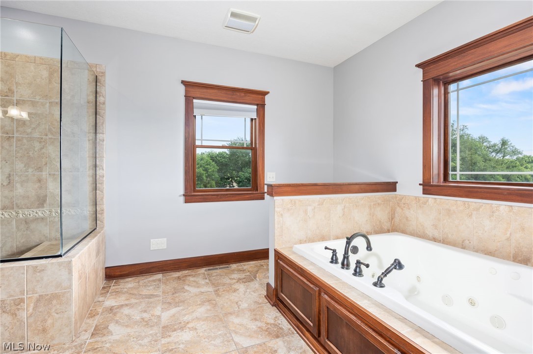 6925 River Styx Road Medina, OH 44256 - Photo 28 of 49 Built-in jetted tub with dark bronze fixtures, framed by warm wood trim and light-toned tile surround