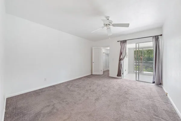 an empty room with chandelier fan and windows