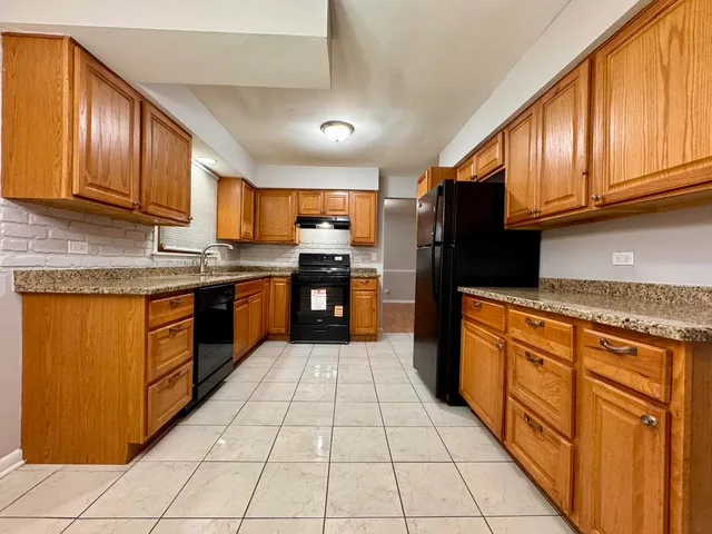 a kitchen with stainless steel appliances granite countertop wooden cabinets a stove top oven a sink and dishwasher