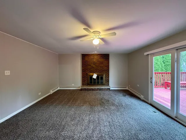 a view of an empty room with window and chandelier fan