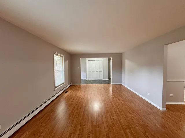 a view of an empty room with wooden floor and window