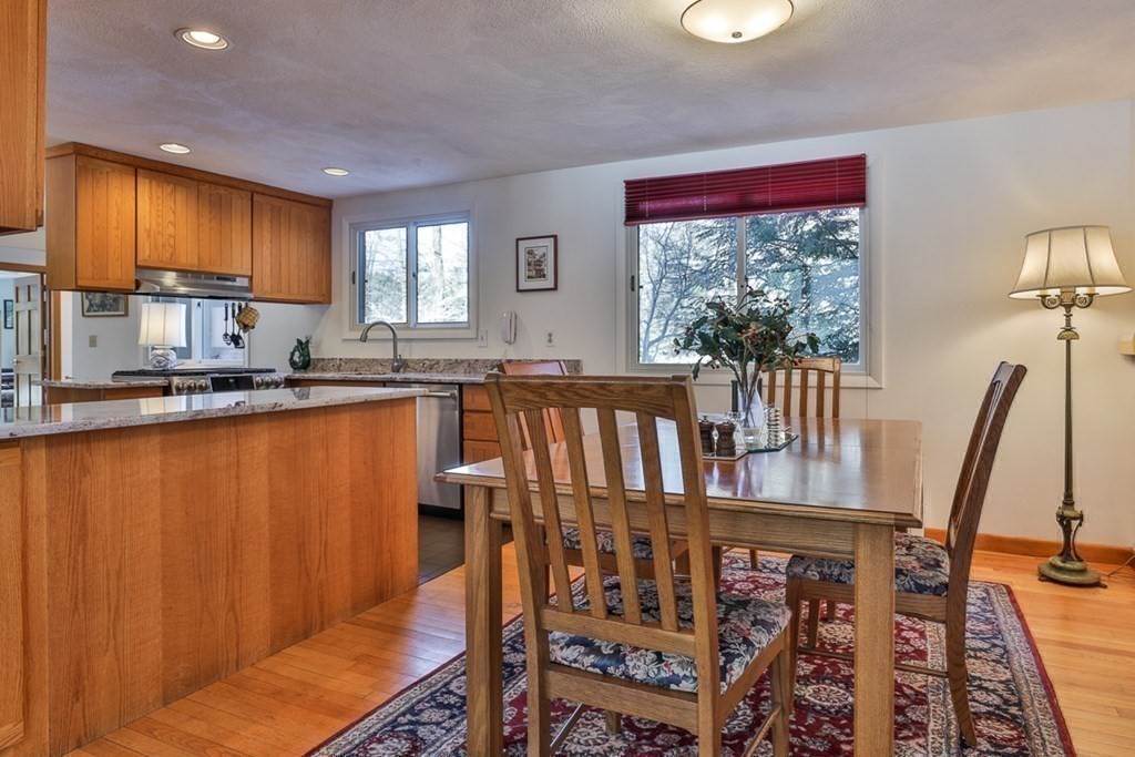 121 West Bare Hill Road Harvard, MA 01451 - Photo 10 of 36 a kitchen with stainless steel appliances granite countertop a refrigerator a stove top oven and a dining table with wooden cabinet