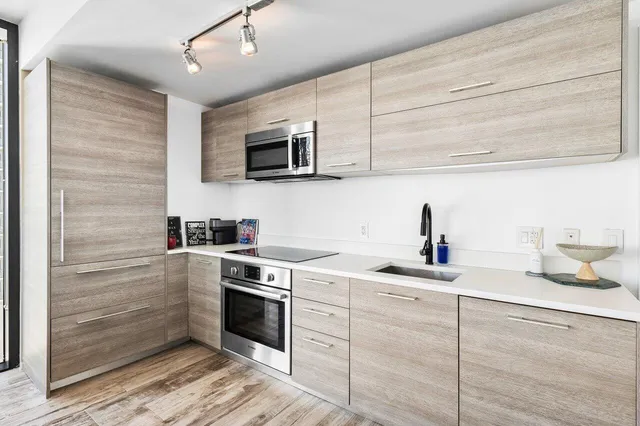 a kitchen with cabinets stainless steel appliances and sink