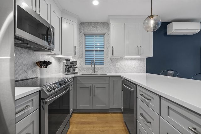 a kitchen with stainless steel appliances a sink dishwasher a stove a microwave oven with cabinets and wooden floor