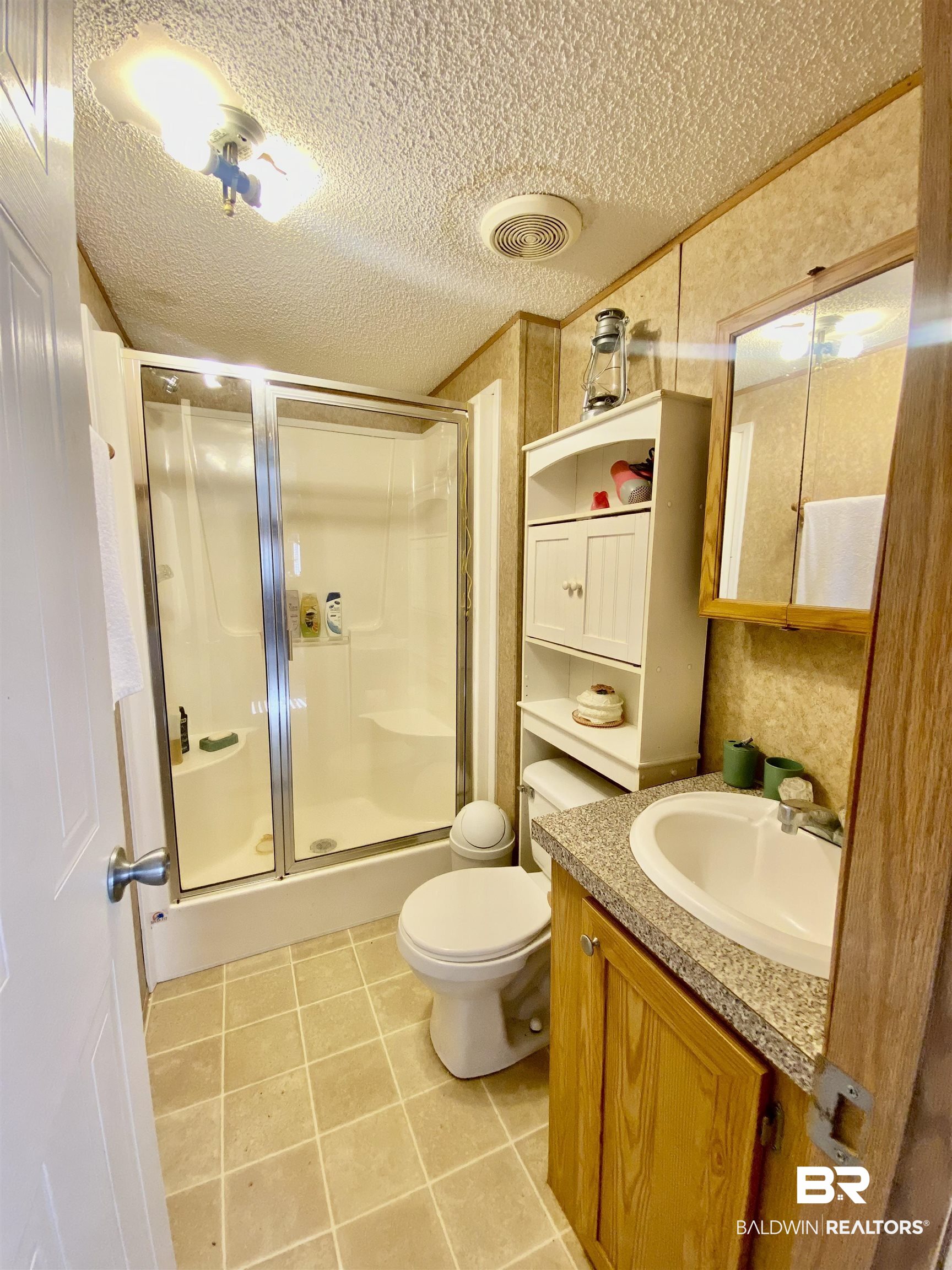 294 Eureka Way Uriah, AL 36480 - Photo 11 of 18 Bathroom with a textured ceiling, tile patterned flooring, vanity, visible vents, and a shower stall