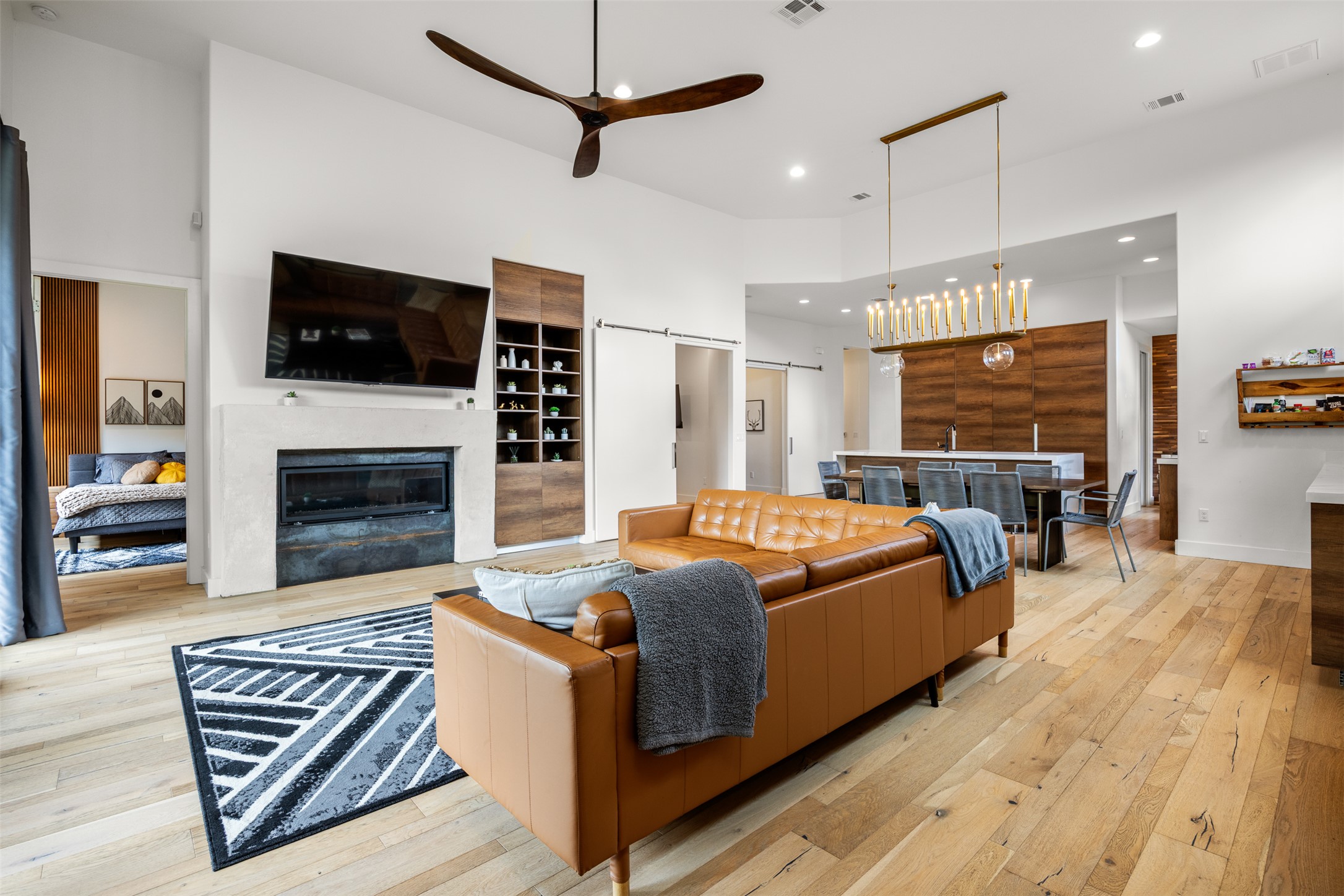 4103 Ridgelea Drive Austin, TX 78731 - Photo 11 of 26 Blonde hardwood floors flow through an open-concept living area with a fireplace and modern light fixtures.