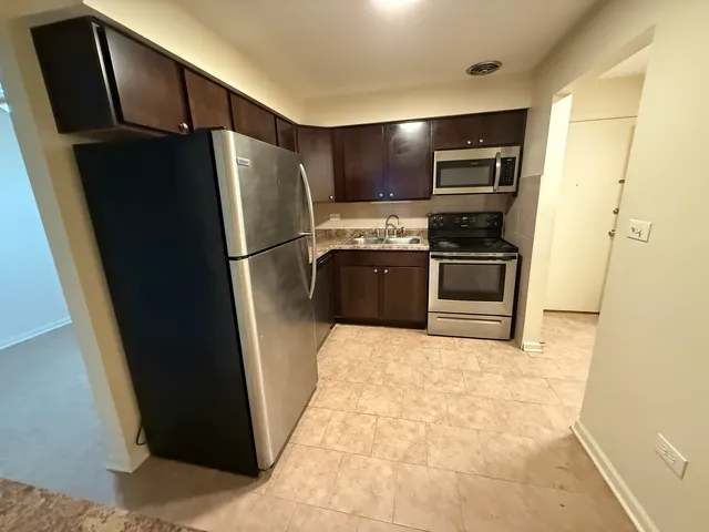 a kitchen with stainless steel appliances granite countertop a refrigerator a stove and a sink