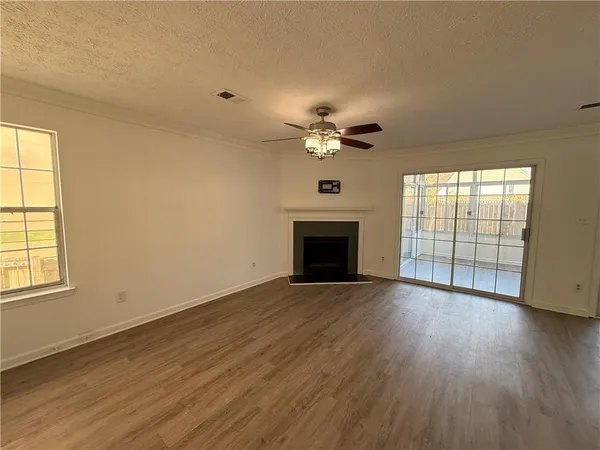 an empty room with wooden floor fan and windows