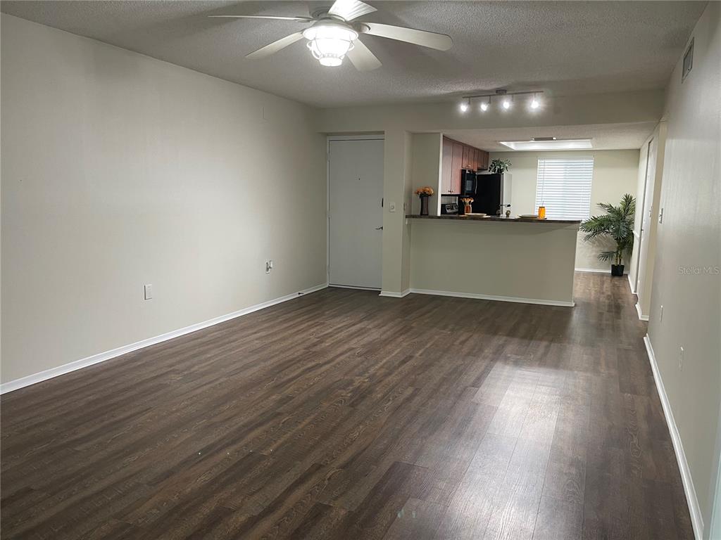 112 Palmetto Court, Unit 112 Oldsmar, FL 34677 - Photo 13 of 46 an empty room with wooden floor and kitchen view