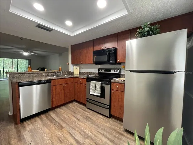 a kitchen with stainless steel appliances granite countertop a refrigerator a stove a sink and a microwave